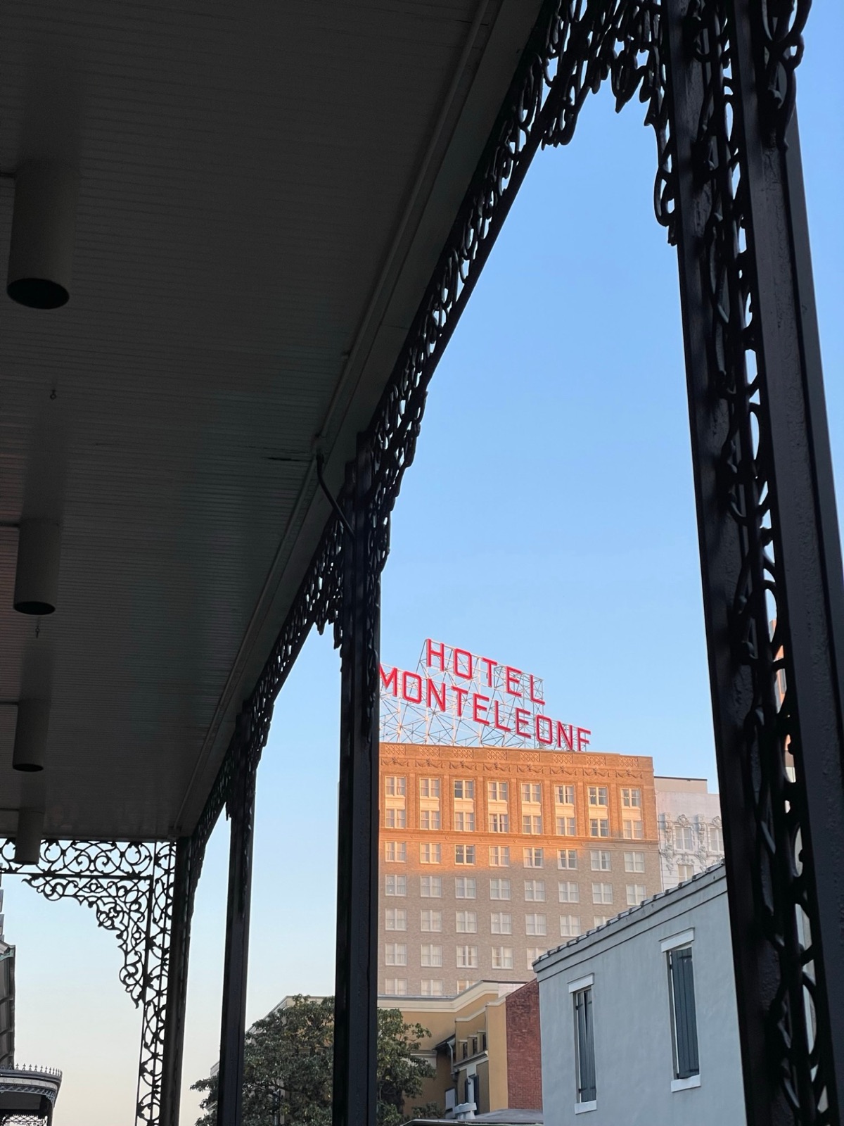 Hotel Monteleone sign glowing at dusk through wrought-iron balconies