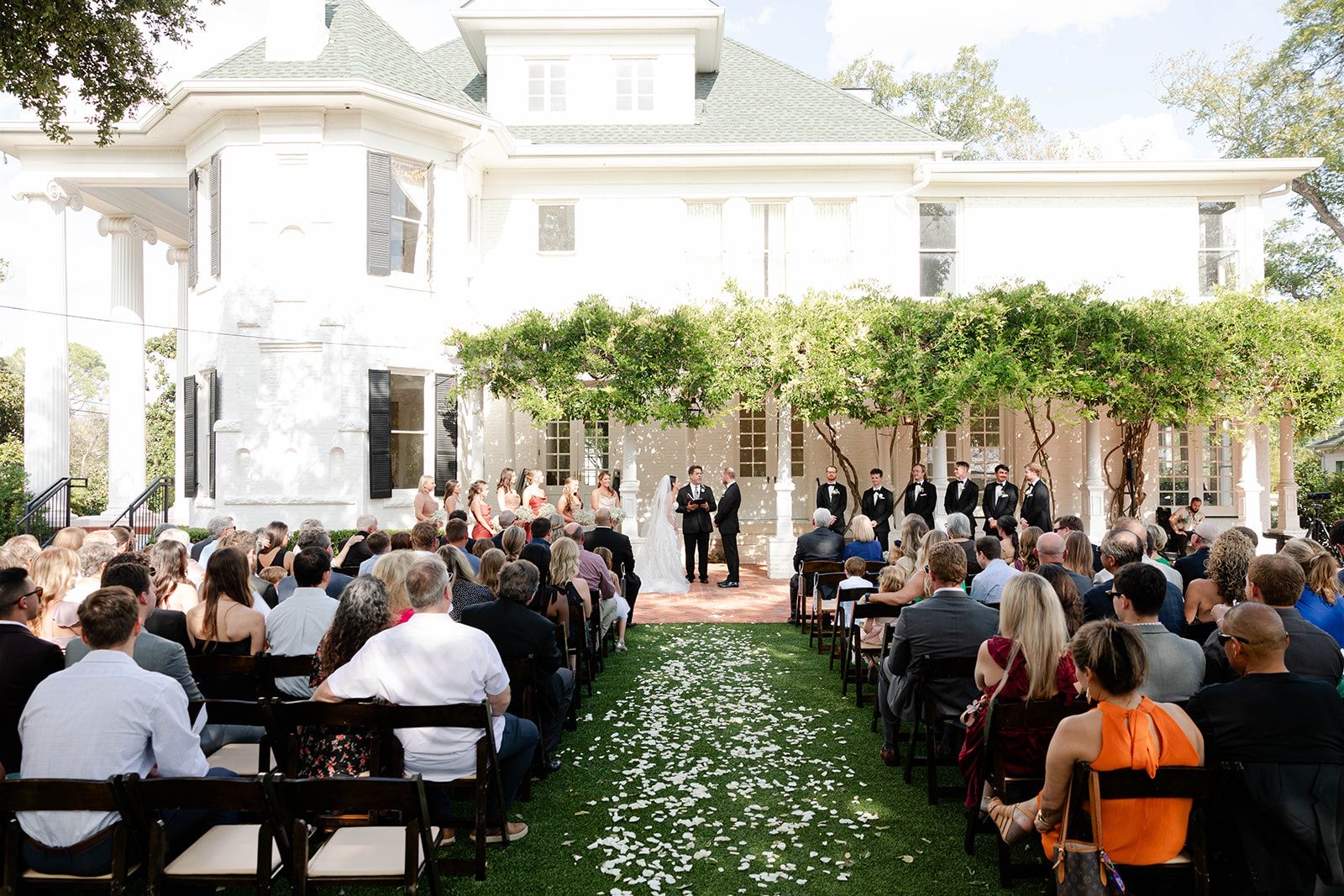 An outdoor wedding ceremony in front of a white house