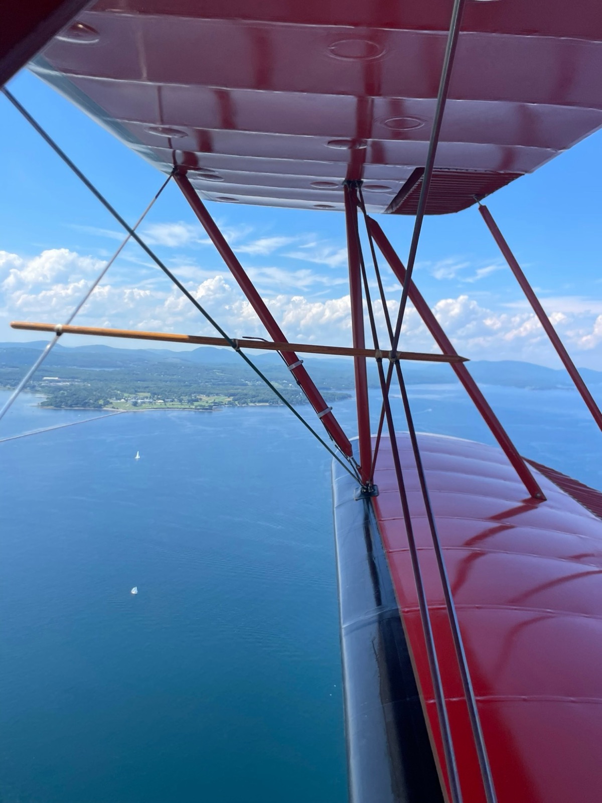 View over the wing of a red biplane above the water